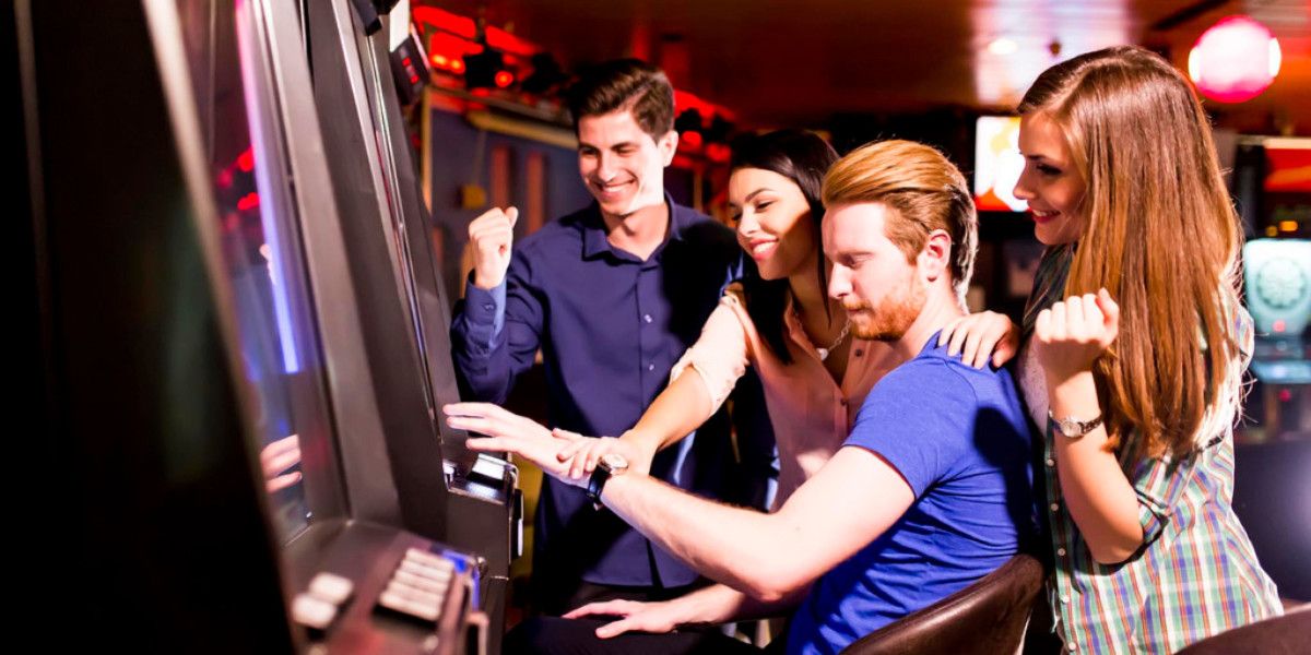 group of young people playing slot machine games in casino